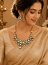 Gold kundan statement necklace set with green teardrop stones and matching earrings