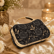 Black floral clutch bag with gold handle and dark fabric with large flower motifs