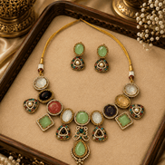 Gold-toned necklace set with oval and teardrop green, gold, and black stones on tray