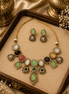 Gold-toned necklace set with oval and teardrop green, gold, and black stones on tray