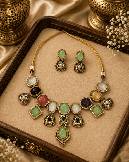 Gold-toned necklace set with oval and teardrop green, gold, and black stones on tray