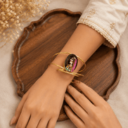 Gold-tone open cuff bracelet with oval enamel face, worn on wrist