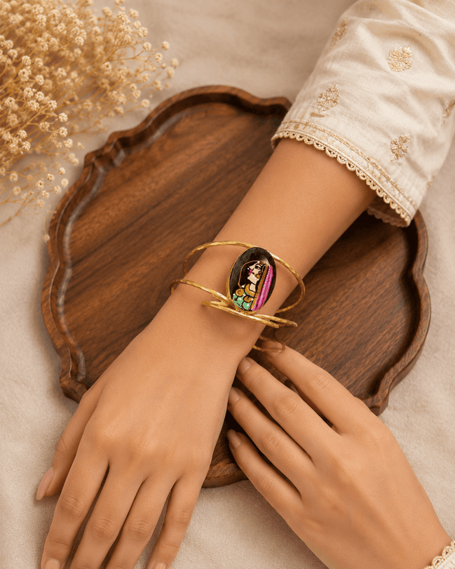 Gold-tone open cuff bracelet with oval enamel face, worn on wrist