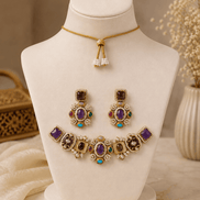 Gold-tone necklace set with purple, black, and teal gemstones; matching drop earrings