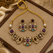 Gold-tone necklace set with purple and teal gemstones on tray; matching drop earrings