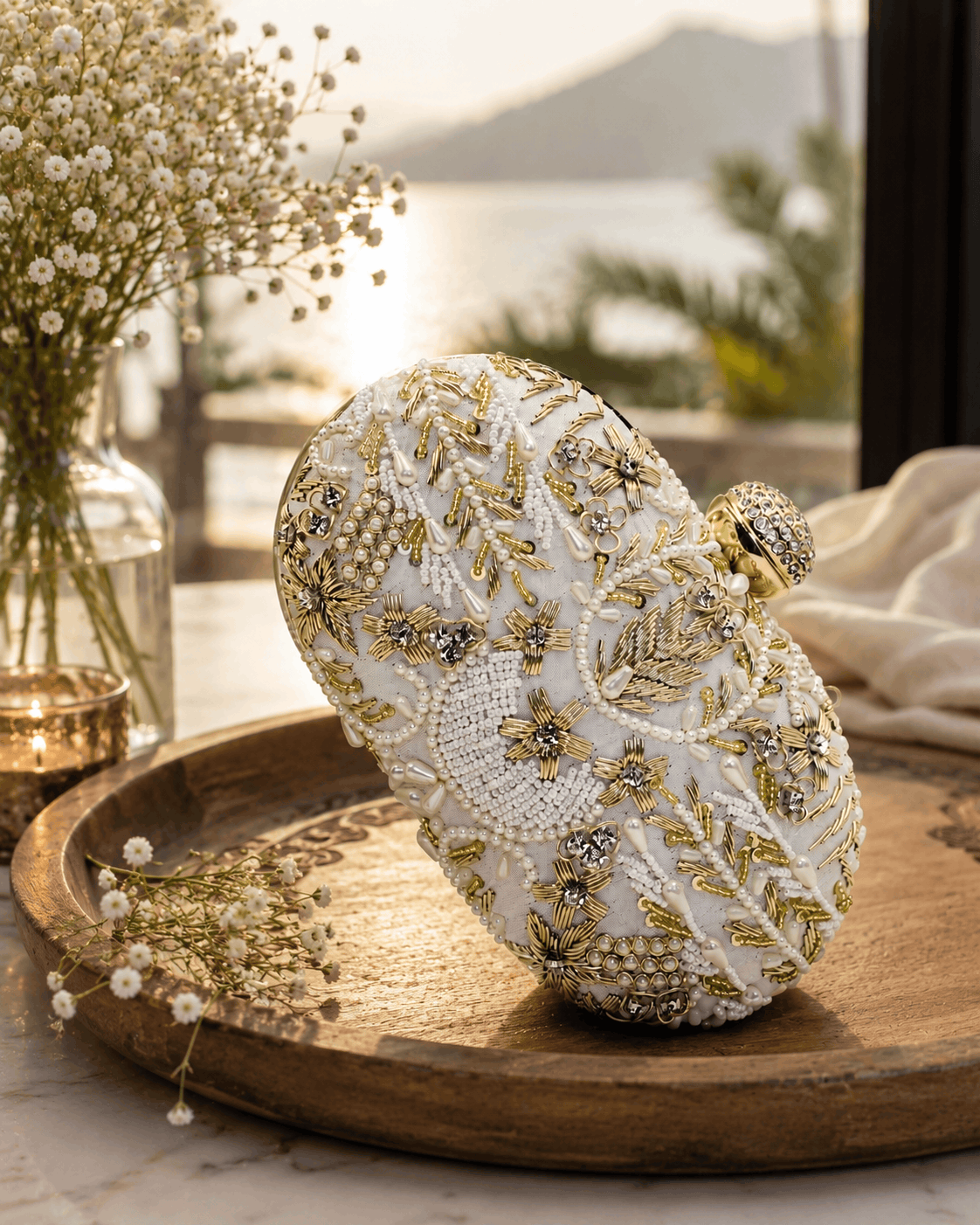 White beaded clutch with gold-toned floral and star motifs; rounded top and clasp.