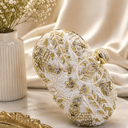 White beaded clutch close-up with gold-toned embellishments; rounded top with gold clasp.