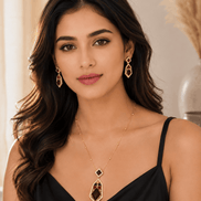 Gold-tone pendant necklace and drop earrings with dark red and blue stones, worn.